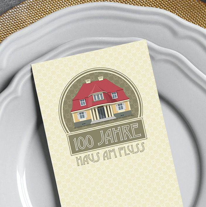 Festliche Menükarte mit Illustration eines Hauses und Schriftzug „100 Jahre Haus am Fluss“ auf Porzellanteller – Design: Isabel Gewecke.