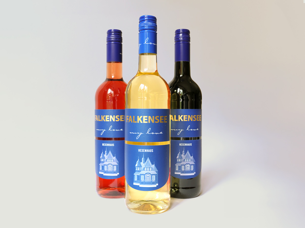 Drei Weinflaschen mit Etikett „Falkensee my love“ und Hexenhaus-Illustration – Design: Isabel Gewecke.